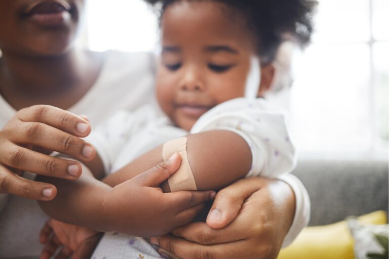 Child with a bandage being held by parent